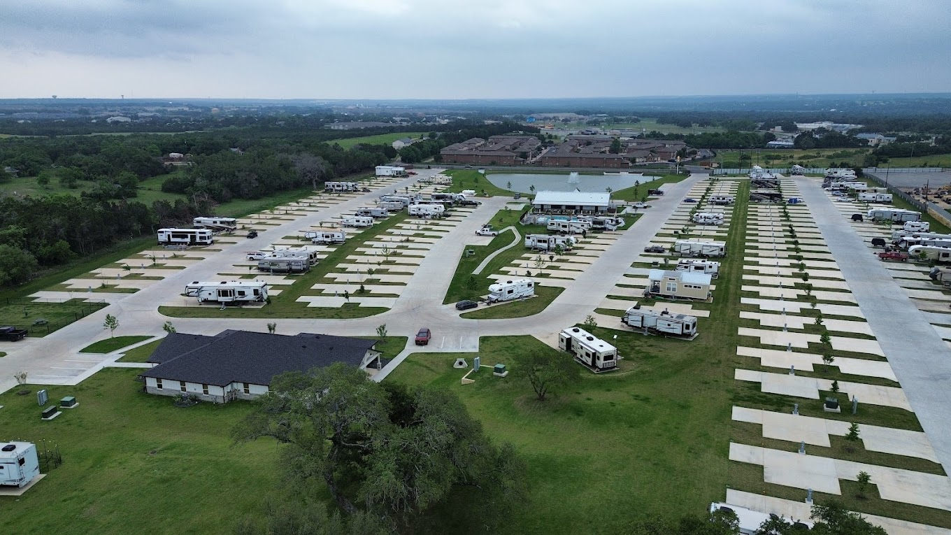 RV Park with Concrete Pads and Spacious Layout – A large, modern RV park offering wide concrete pads, green spaces, and a mix of covered and uncovered sites, ideal for a variety of travelers and long-term residents.