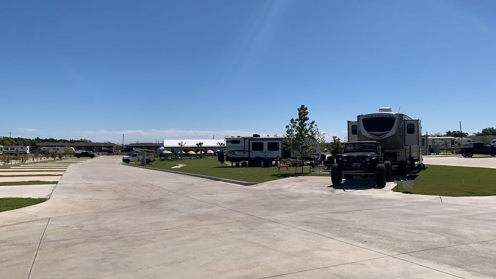 RV Site with Lush Greenery and Open Space – A well-maintained RV park with paved roads, green lawns, and spacious sites, offering a balance of natural beauty and modern amenities for RV living.