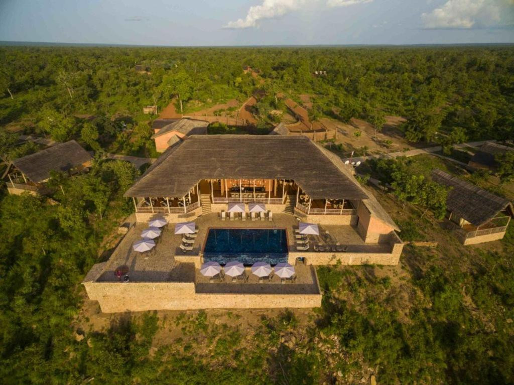 Aerial view of Zaina Lodge in Ghana, showcasing its main lodge with a thatched roof, an expansive pool deck with umbrellas, and surrounding luxury safari tents nestled in lush greenery. This premier glamping destination exemplifies high-end outdoor hospitality, an area explored by Sage Outdoor Advisory in its feasibility studies.