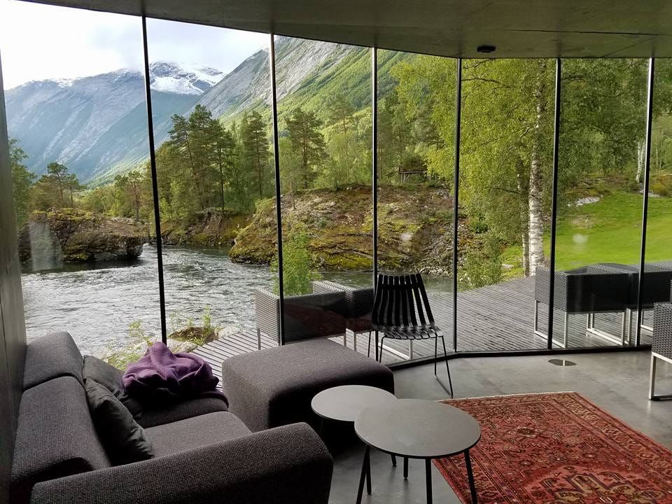 A breathtaking glass-walled suite overlooking a serene river and lush mountains. This landscape hotel blends modern minimalist design with nature, offering an immersive stay in a tranquil, eco-conscious retreat. Blog post by Sage Outdoor Advisory, offering Glamping and RV Feasibility Studies