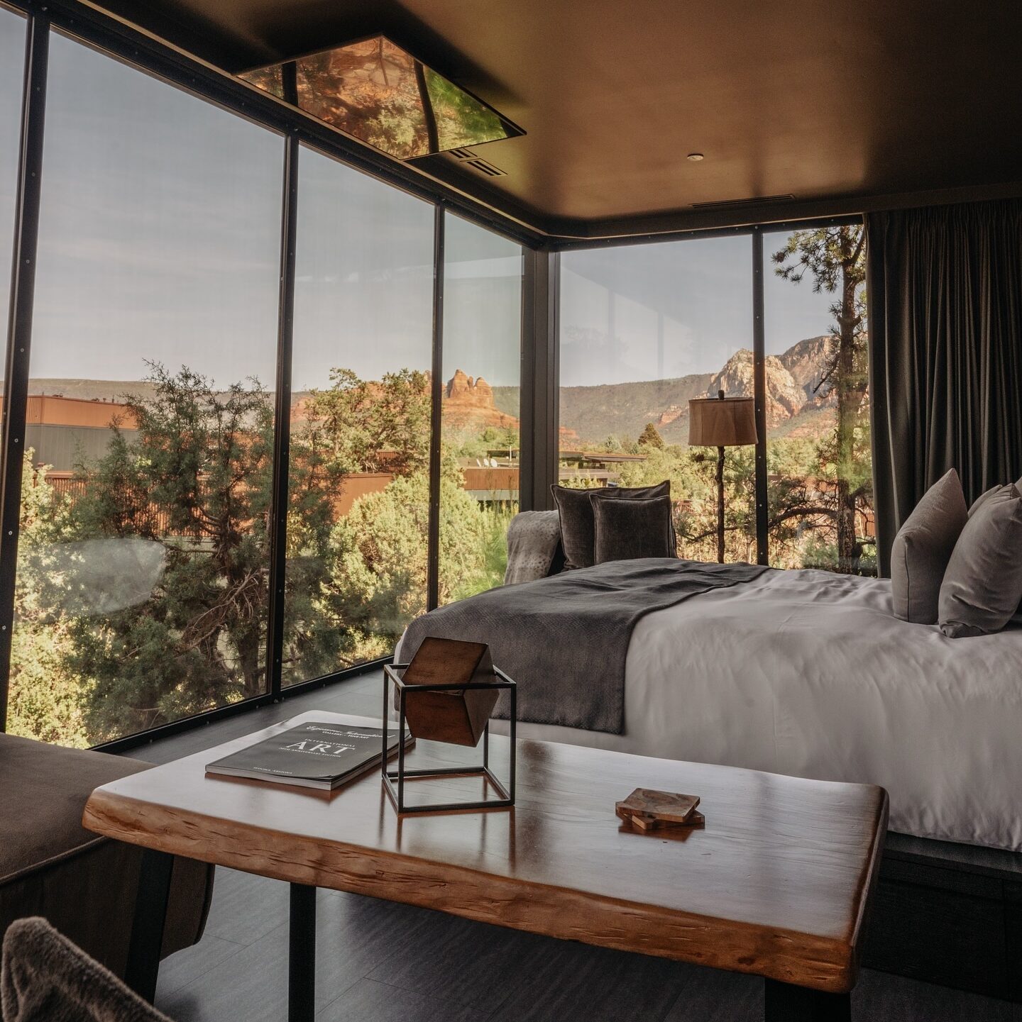 A luxurious glass-walled suite at Ambiente: A Landscape Hotel in Sedona, offering uninterrupted views of the stunning red rock formations. Designed for eco-conscious travelers, this nature-immersive retreat blends sustainability with high-end comfort.