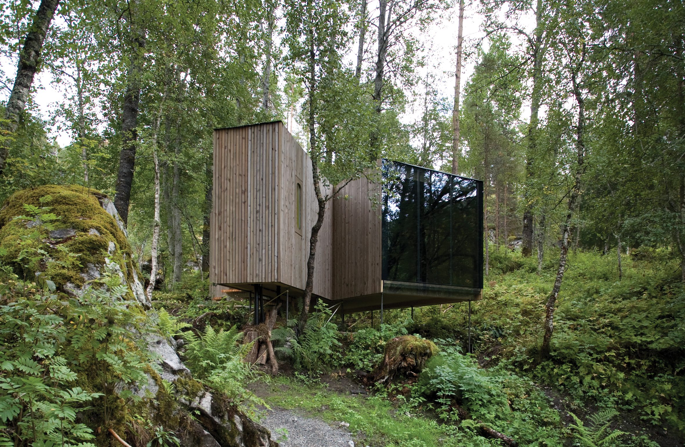 A stunning eco-friendly cabin at Juvet Landscape Hotel in Norway, designed to blend seamlessly into the lush forest. Featuring floor-to-ceiling glass walls, this minimalist retreat offers an immersive nature experience with sustainable architecture.