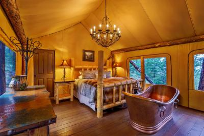 Interior of a luxury glamping tent featuring a rustic wooden bed, copper bathtub, and chandelier lighting—an example of high-end accommodations analyzed in a Sage Outdoor Advisory feasibility study for glamping resort development.