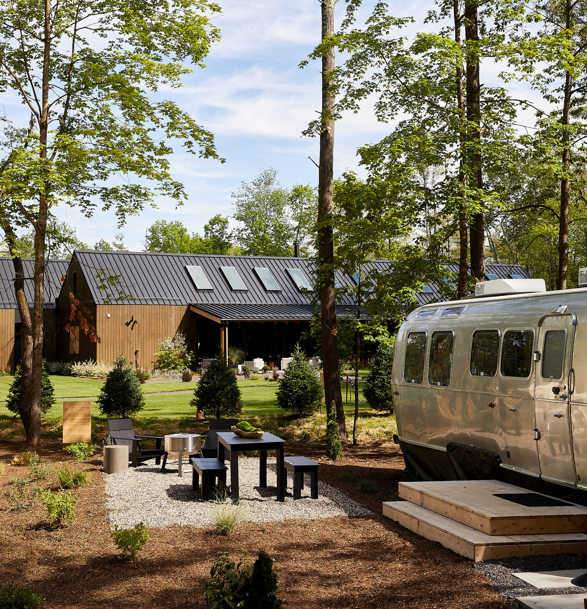 Modern glamping setup with an Airstream trailer and outdoor seating area surrounded by trees, representing unique lodging types included in Sage Outdoor Advisory’s glamping feasibility studies.