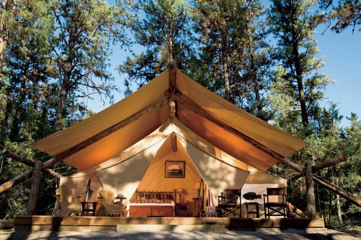 Classic canvas glamping tent nestled in a forest setting, showcasing nature-focused design elements reviewed in Sage Outdoor Advisory’s glamping feasibility reports.