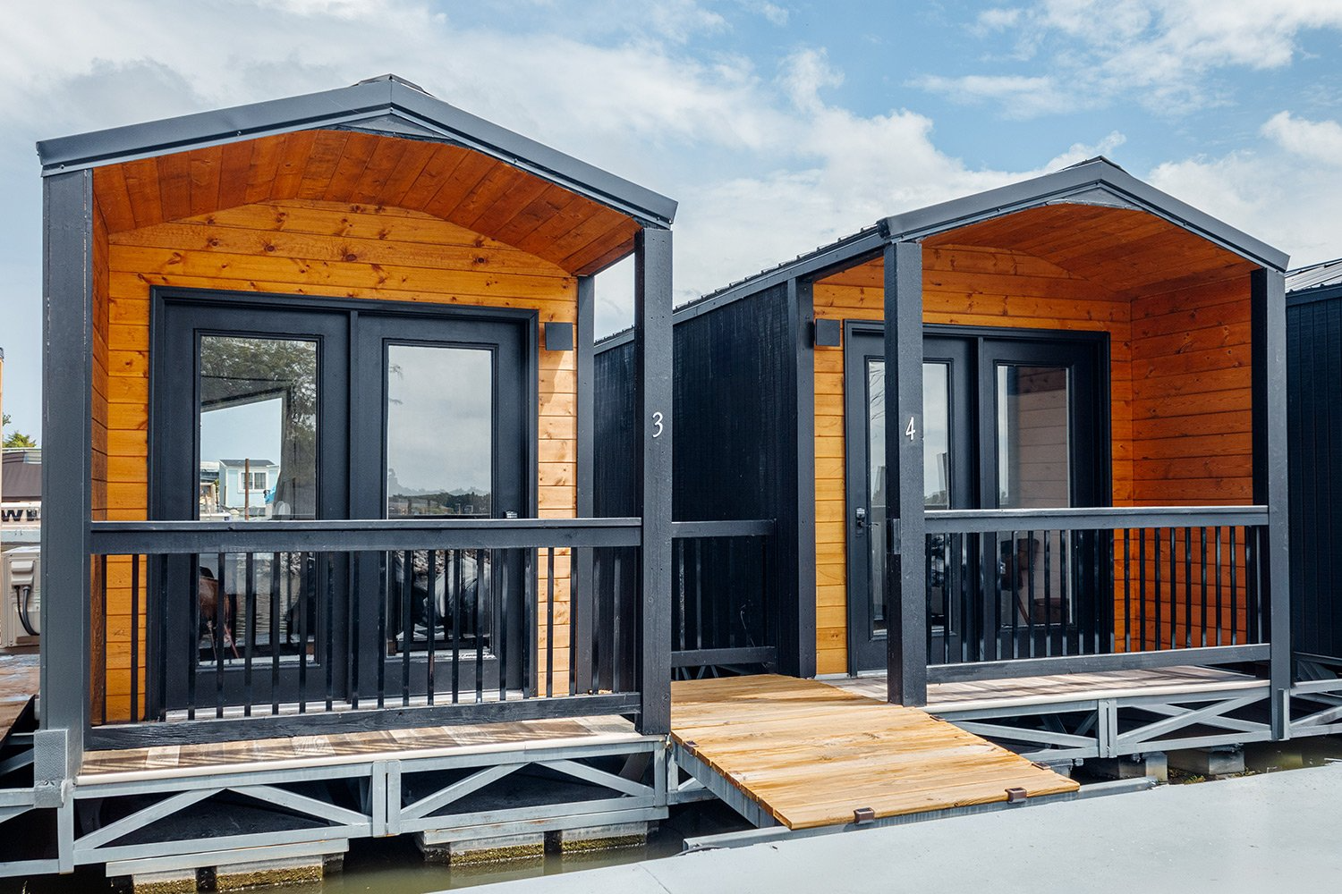 Modern floating glamping cabins at Soul Stay with natural wood siding, black metal trim, and dock-level access, representing an innovative blend of outdoor lodging and maritime design. These luxury units were part of a successful glamping development project that underwent a feasibility study led by Sage Outdoor Advisory to assess market fit and long-term viability.