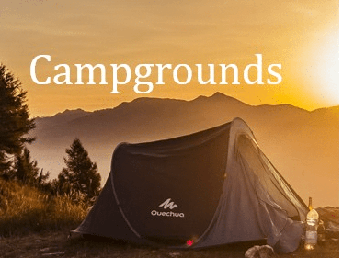 A Quechua tent set up in a scenic campground with a stunning sunset backdrop, featuring a golden sky, mountains, and a mix of pine trees in the foreground. The word 'Campgrounds' is prominently displayed at the top.