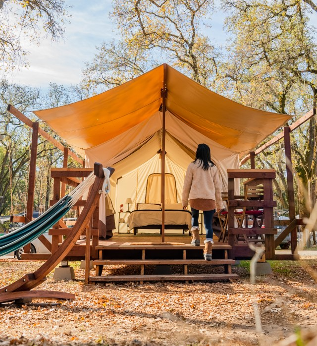 A guest walks into a canvas glamping tent, showcasing cozy and elevated outdoor accommodations often featured in Sage Outdoor Advisory glamping feasibility studies.