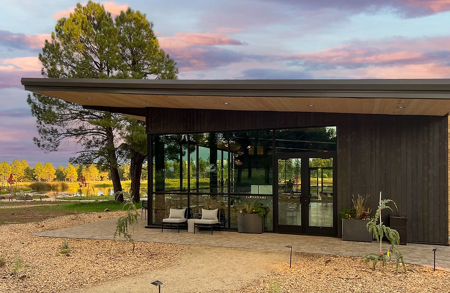 A modern single-story hospitality building with dark wood siding, expansive glass walls, and minimalist furnishings, set against a pink and purple sunset in a pine forest.
Sage Outdoor Advisory supports partners like Clockwork by providing site-specific feasibility studies, market research, and financial analysis that ensure outdoor hospitality projects are not just visionary but feasible.