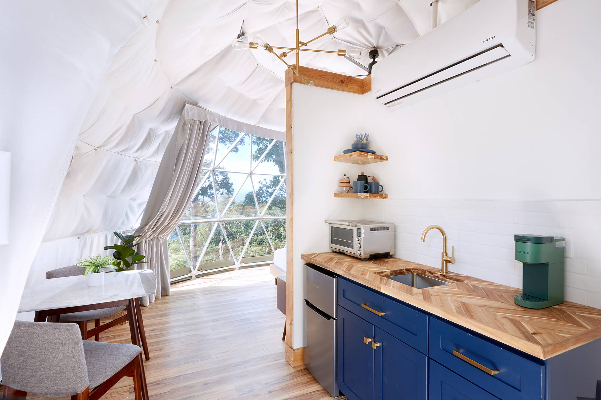Interior of a luxury geodome rental with kitchenette and mountain views, designed to highlight guest experience. Sage Outdoor Advisory provides feasibility studies and consulting for glamping and outdoor resort developments like this.