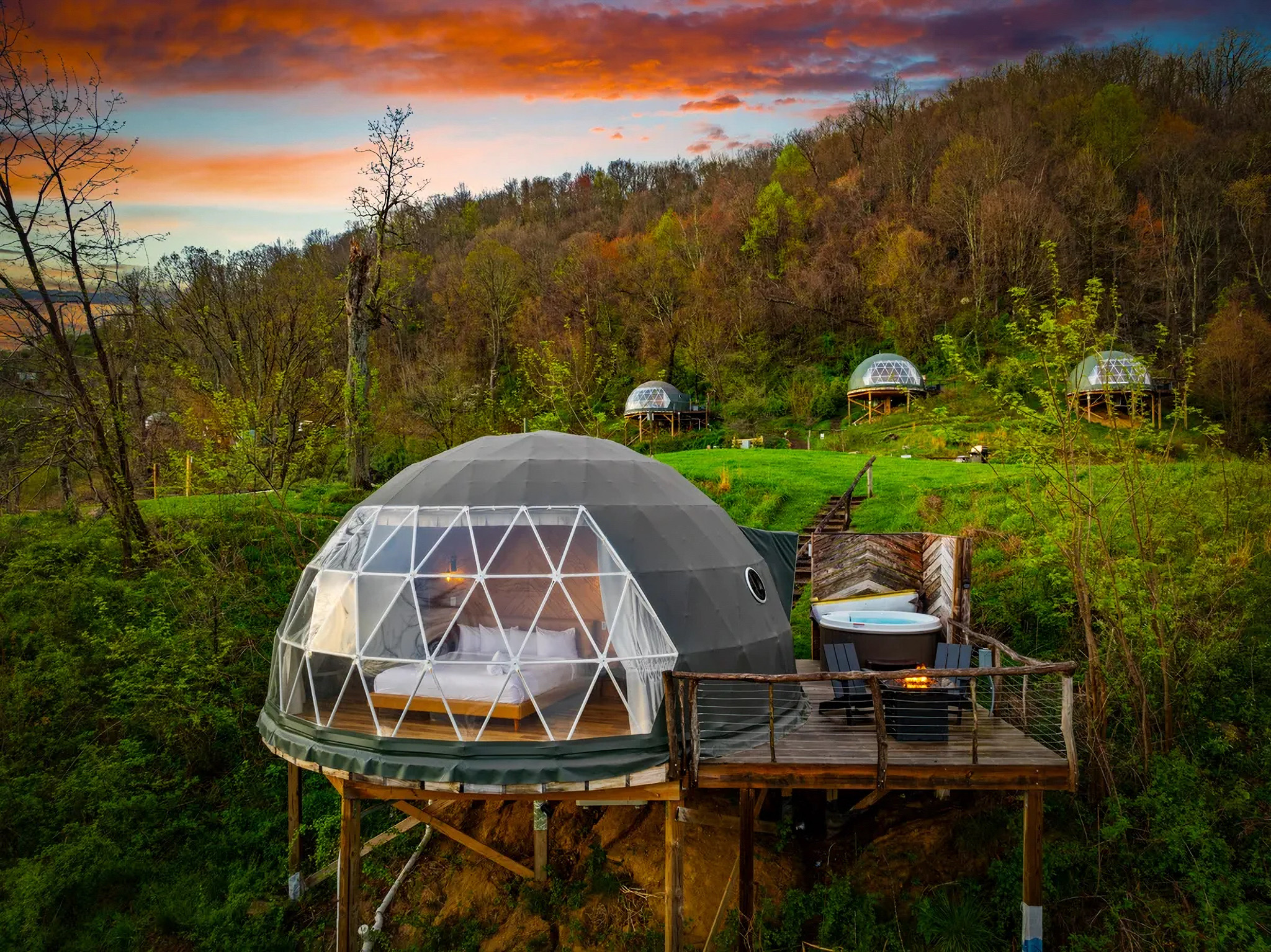 Luxury geodome glamping unit with recessed hot tub on private deck at sunset. Sage Outdoor Advisory offers appraisals, feasibility studies, and consulting for unique outdoor lodging developments.