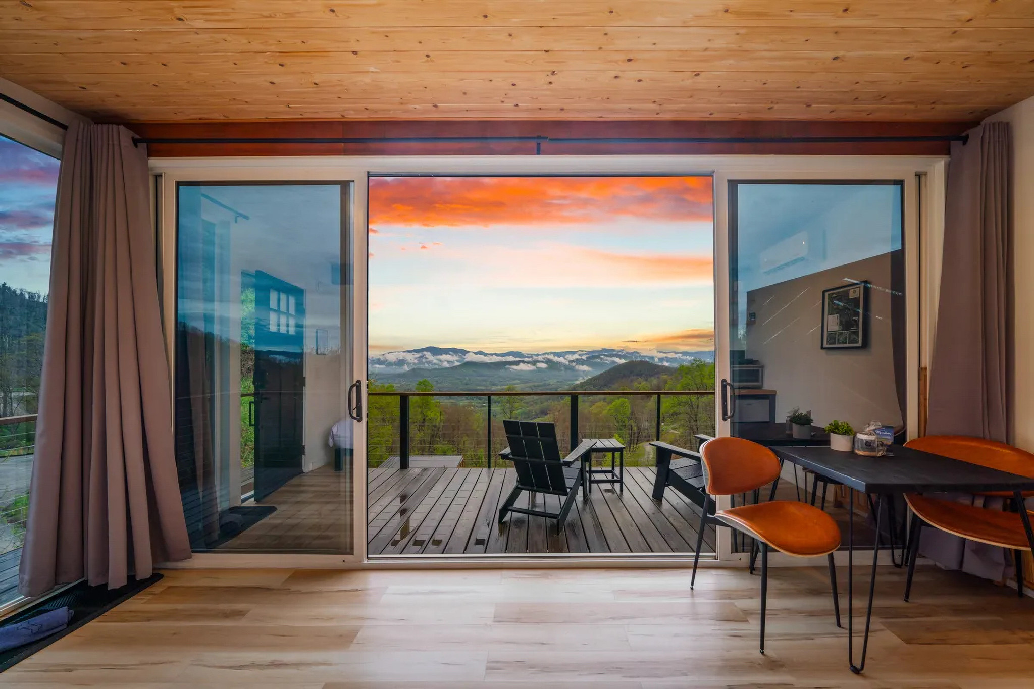 Glass cabin rental with sliding doors opening to mountain views at The Glamping Collective. Sage Outdoor Advisory assists developers with feasibility studies, appraisals, and pitch decks for profitable glamping resorts.