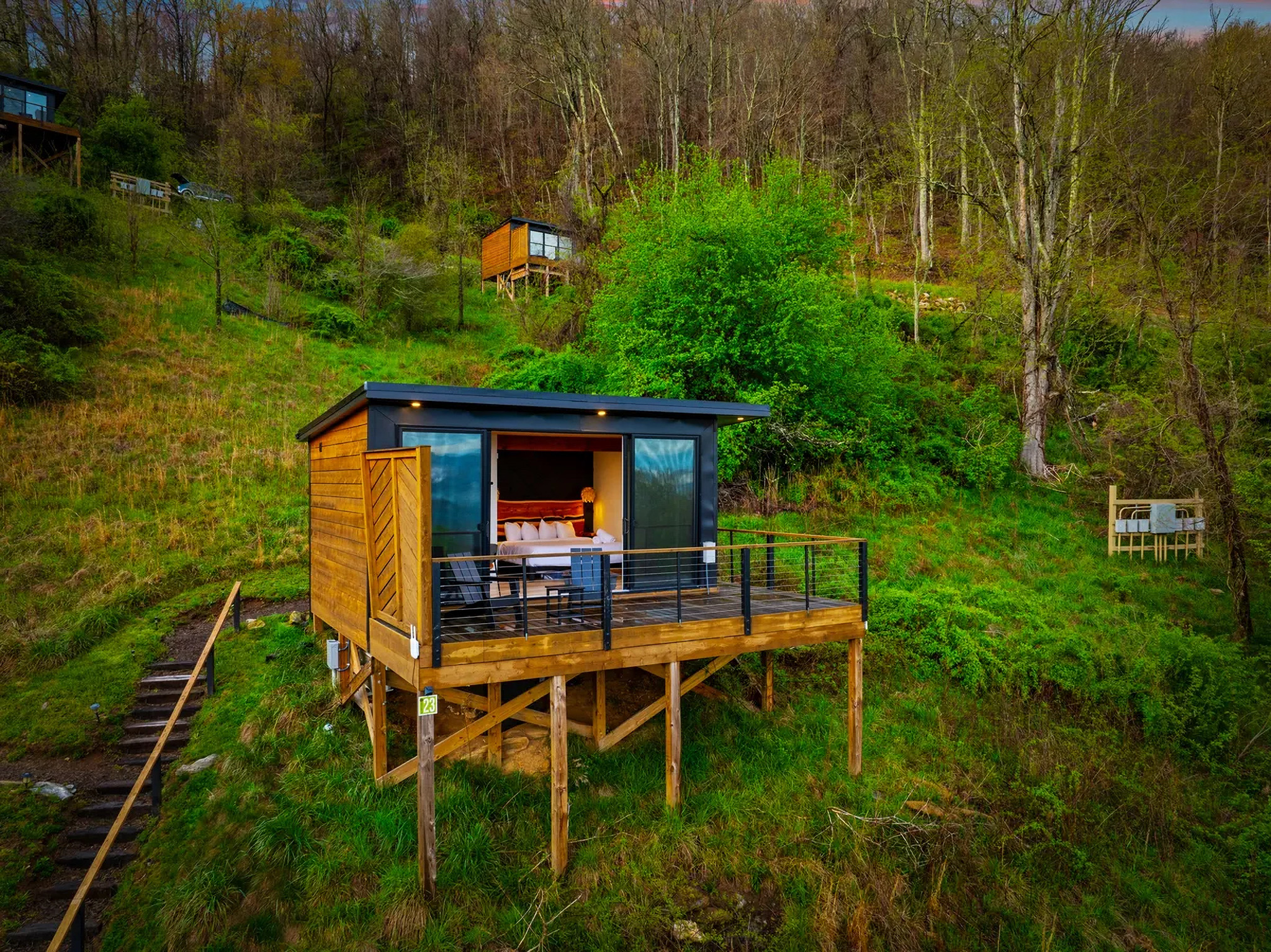 Modern glass cabin perched on a mountainside with expansive outdoor deck. Sage Outdoor Advisory delivers market analysis, feasibility studies, and consulting for outdoor resort development and investment.