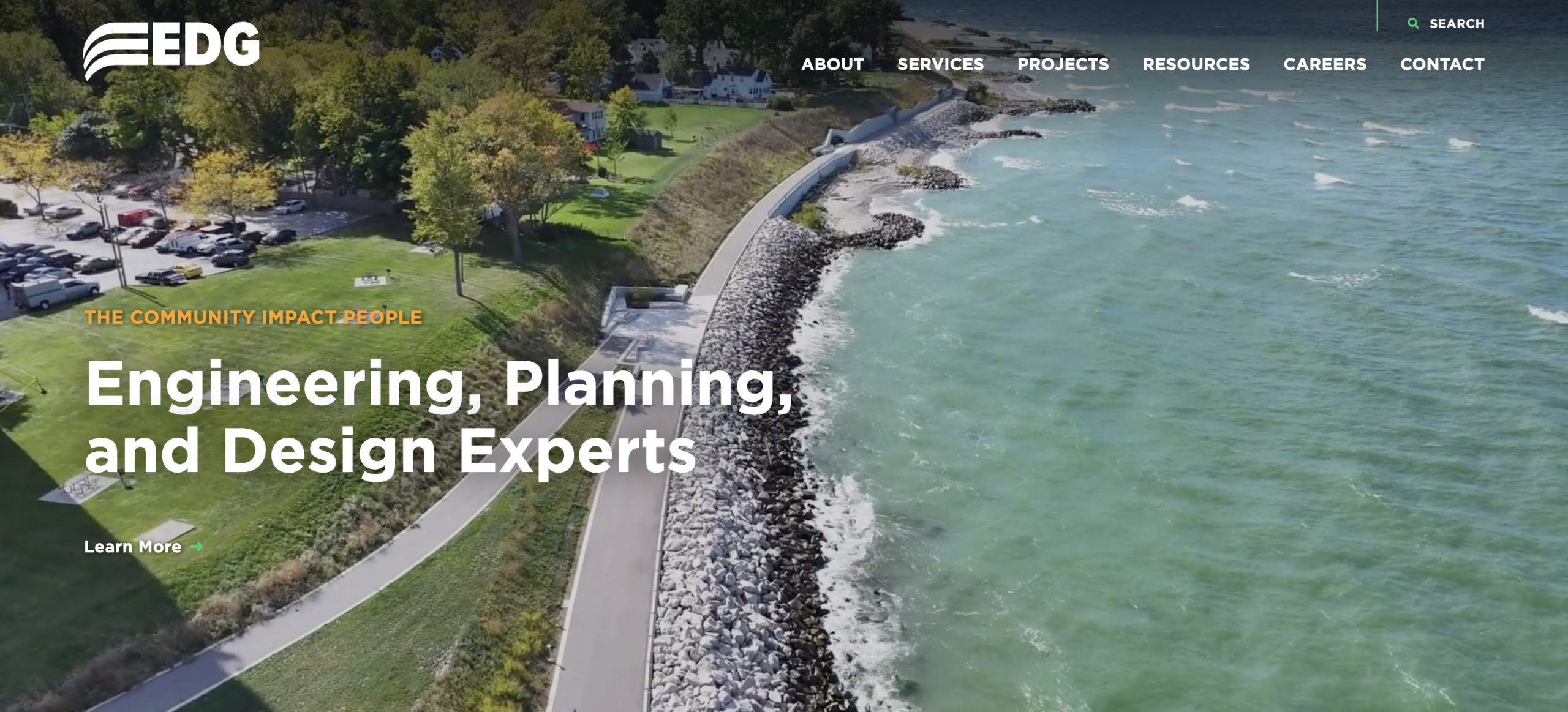EDG (Environmental Design Group) homepage banner showing an aerial view of a lakeshore park with a curving shoreline path and rocky breakwater, featuring the headline “Engineering, Planning, and Design Experts.