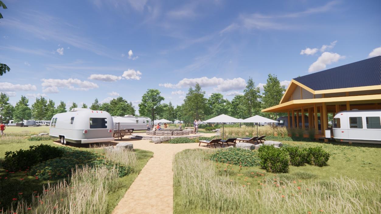 Bernard Architects rendering of a high-end RV resort, featured in the Sage Outdoor Advisory Partner Spotlight. Two silver Airstream trailers sit on landscaped sites in the foreground and midground, separated by native grasses, low shrubs, and wildflowers under a sunny sky. A decomposed granite path leads toward a central stone fire pit where a small group of guests is gathered, with white shade umbrellas and lounge chairs nearby. At right, a clubhouse building with a wood-framed covered porch and a dark standing-seam metal roof anchors the scene, with additional RVs and trees visible in the background.